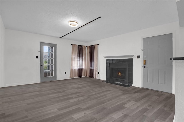 unfurnished living room featuring wood finished floors, a textured ceiling, and a tile fireplace