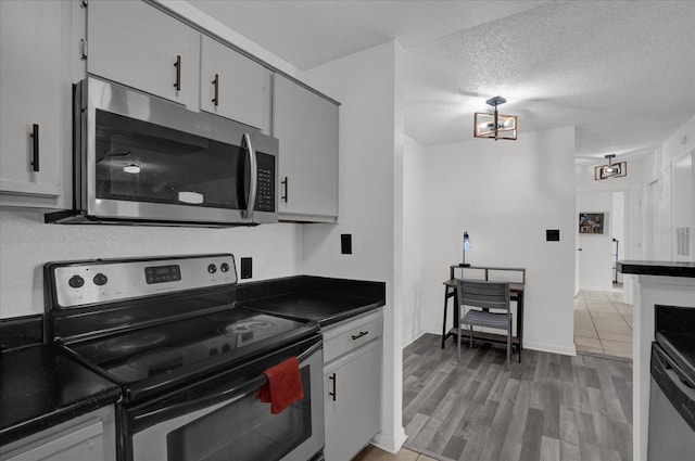 kitchen featuring appliances with stainless steel finishes, dark countertops, a textured ceiling, and light wood-type flooring
