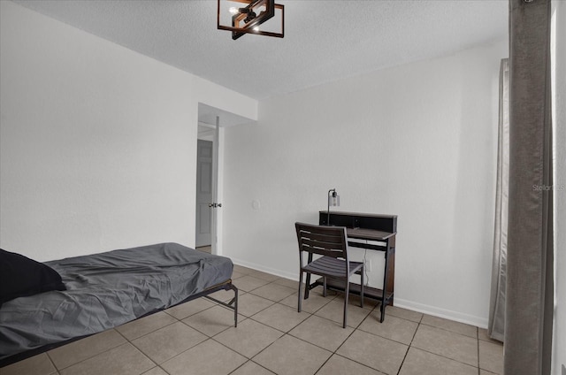 bedroom featuring light tile patterned floors, a textured ceiling, and baseboards