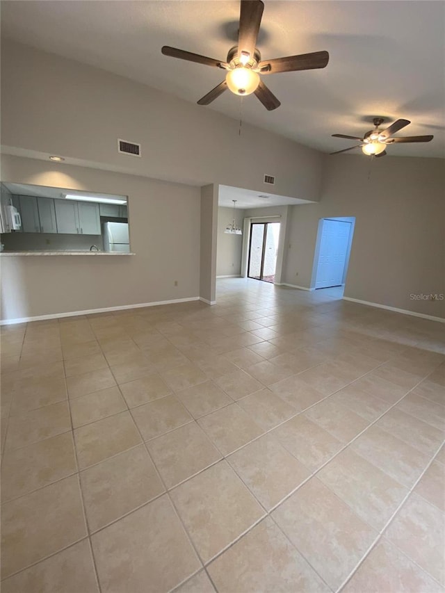 unfurnished living room featuring light tile patterned flooring, a ceiling fan, and baseboards