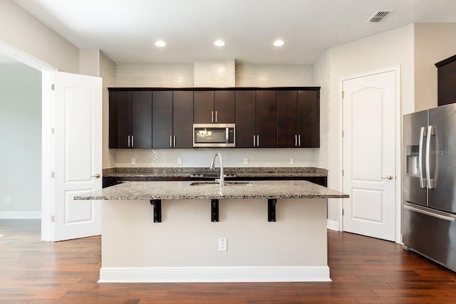 625 Pavia Loop, Lake Mary, FL 32746 - kitchen with appliances with stainless steel finishes, a breakfast bar area, a sink, light stone countertops, and a center island with sink