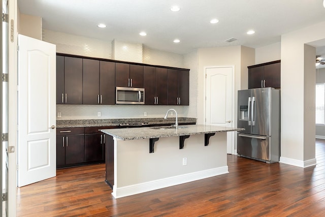 625 Pavia Loop, Lake Mary, FL 32746 - kitchen with stainless steel appliances, a sink, a breakfast bar area, dark wood-style floors, and recessed lighting