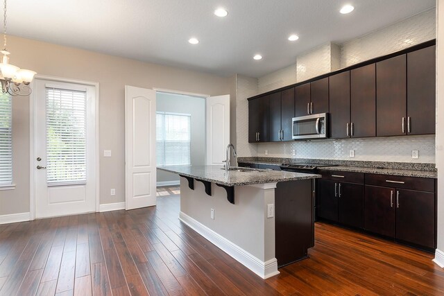 625 Pavia Loop, Lake Mary, FL 32746 - kitchen featuring stainless steel microwave, a sink, a breakfast bar, an island with sink, and a chandelier