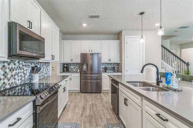 2539 Auburn Ridge Dr, Apopka, FL 32712 - kitchen with stainless steel appliances, a sink, white cabinetry, light wood-style flooring, and recessed lighting