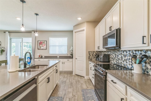 2539 Auburn Ridge Dr, Apopka, FL 32712 - kitchen featuring stainless steel appliances, a sink, light wood-style flooring, decorative backsplash, and a textured ceiling
