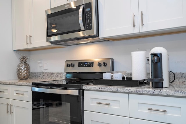 kitchen featuring appliances with stainless steel finishes, white cabinetry, and light stone counters