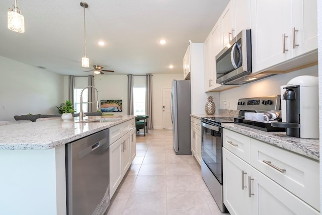 kitchen featuring appliances with stainless steel finishes, a sink, an island with sink, a ceiling fan, and open floor plan