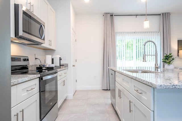 kitchen with appliances with stainless steel finishes, a sink, light stone countertops, white cabinets, and decorative light fixtures