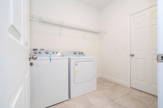 laundry area featuring washing machine and clothes dryer, light tile patterned floors, and baseboards