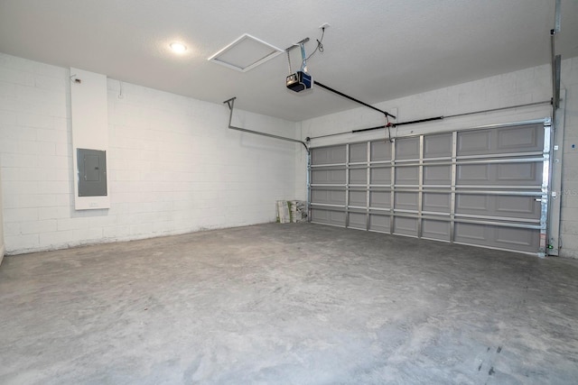 garage with electric panel, a garage door opener, and concrete block wall