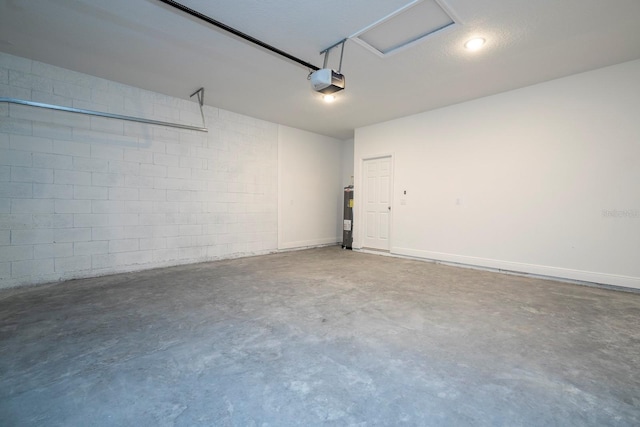 garage with a garage door opener, electric water heater, and concrete block wall