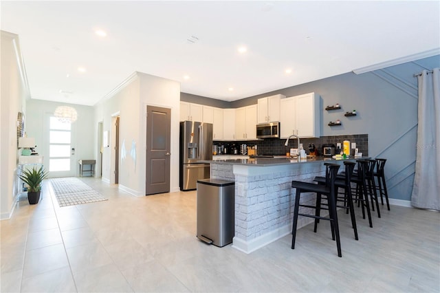 2836 Simile St, Kissimmee, FL 34746 - kitchen with stainless steel appliances, a peninsula, a breakfast bar area, backsplash, and white cabinets
