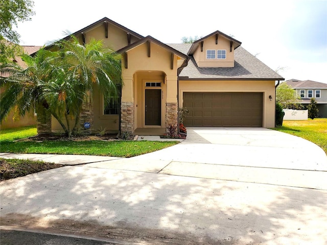 view of front of property with stucco siding, driveway, stone siding, and a garage
