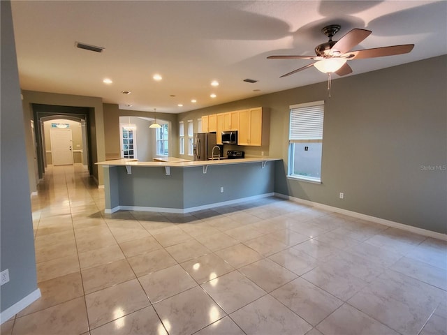 kitchen with appliances with stainless steel finishes, a peninsula, plenty of natural light, light countertops, and recessed lighting