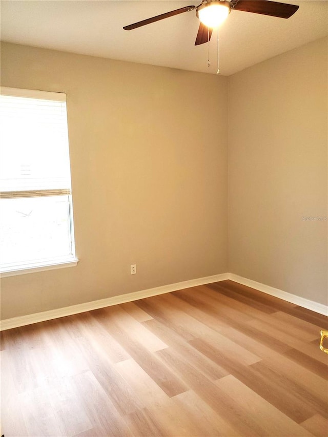 unfurnished room with ceiling fan, wood finished floors, and baseboards