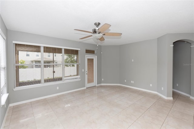 6728 Duncaster St, Windermere, FL 34786 - empty room featuring ceiling fan, arched walkways, baseboards, light tile patterned floors, and a textured ceiling
