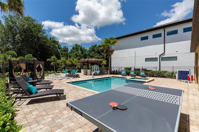 view of swimming pool featuring fence, a patio area, and a pool with connected hot tub