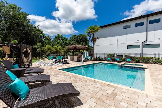 view of swimming pool with a patio area, fence, and a pool with connected hot tub