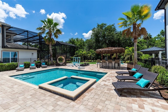 view of swimming pool with a pool with connected hot tub, a patio, fence, and a lanai