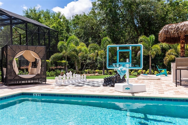 swimming pool featuring a patio area, a lanai, and view of scattered trees