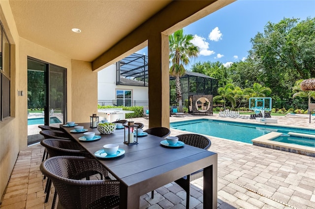 view of swimming pool with a patio area, glass enclosure, a pool with connected hot tub, and outdoor dining area