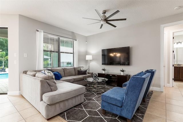 living room with a ceiling fan, tile patterned floors, a textured ceiling, and baseboards