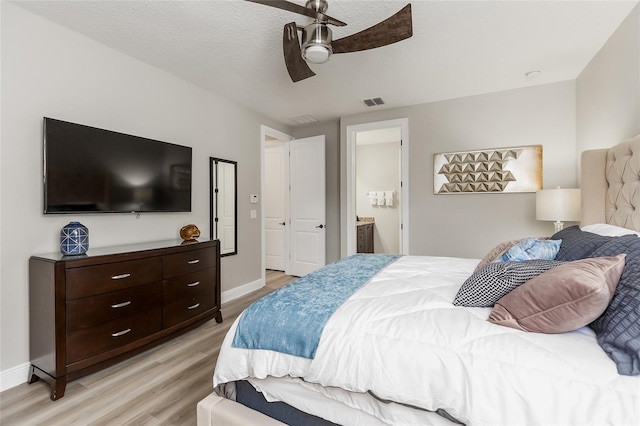 bedroom with light wood-style flooring, baseboards, a ceiling fan, and ensuite bathroom