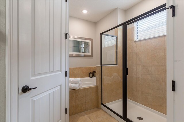 bathroom with a shower stall, a bath, and tile patterned floors