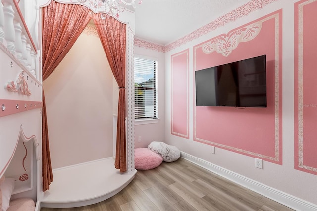 workout room featuring wood finished floors, baseboards, and a chandelier