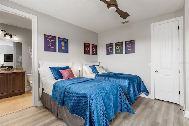 bedroom featuring light wood-style floors, ensuite bathroom, a ceiling fan, and baseboards
