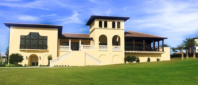 back of house with a lawn, stucco siding, and stairs