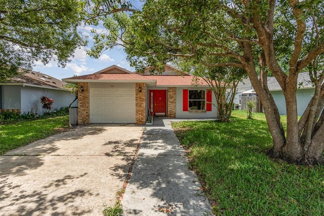 ranch-style home with concrete driveway, a front yard, a garage, and brick siding