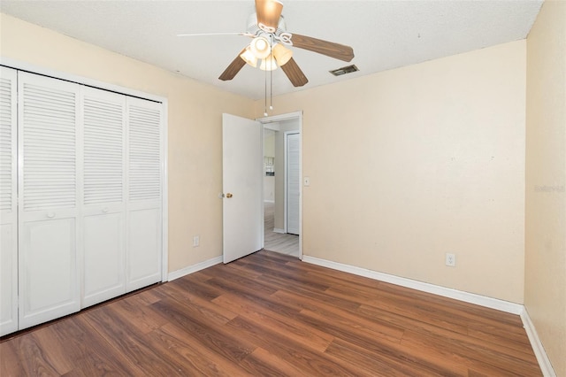 unfurnished bedroom featuring wood finished floors, baseboards, a closet, and ceiling fan