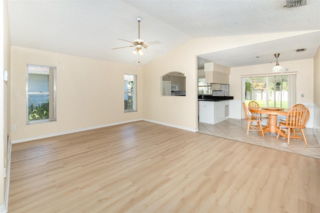 living area with vaulted ceiling, light wood-type flooring, ceiling fan, and baseboards