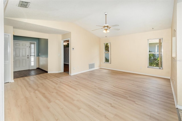 unfurnished room featuring a ceiling fan, healthy amount of natural light, lofted ceiling, and light wood-style floors