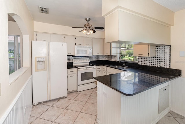kitchen with white appliances, a sink, a peninsula, backsplash, and a ceiling fan