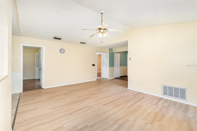 spare room featuring ceiling fan, lofted ceiling, light wood-style floors, and baseboards
