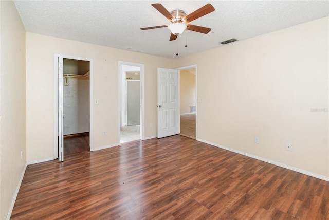 unfurnished bedroom featuring wood finished floors, baseboards, a closet, ceiling fan, and a textured ceiling