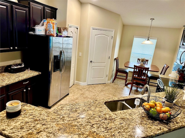 1474 Lakeside Ave, Davenport, FL 33837 - kitchen with stainless steel refrigerator with ice dispenser, light tile patterned floors, hanging light fixtures, light stone counters, and baseboards