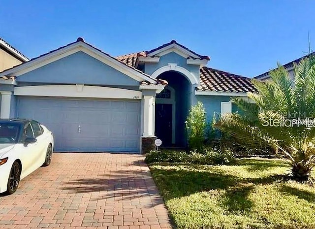 1474 Lakeside Ave, Davenport, FL 33837 - view of front of house with a tiled roof, an attached garage, stucco siding, and decorative driveway