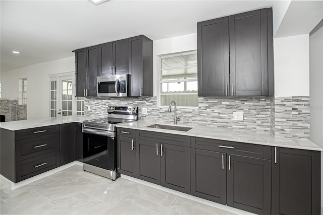 4324 Garden Ave, West Palm Beach, FL 33405 - kitchen with stainless steel appliances, a sink, a peninsula, light marble finish floors, and decorative backsplash