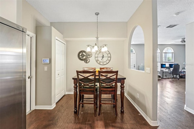 dining room featuring dark wood-style floors, a chandelier, a desk, arched walkways, and ceiling fan
