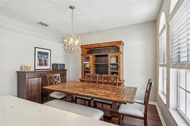 dining area with a chandelier, wood finished floors, a textured ceiling, and baseboards