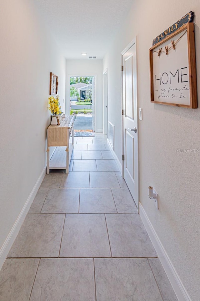 hall with baseboards and light tile patterned floors