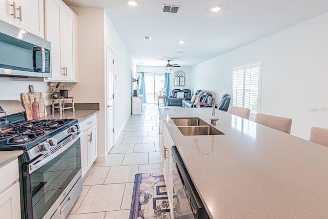 kitchen featuring stainless steel appliances, a sink, light tile patterned floors, recessed lighting, and a ceiling fan