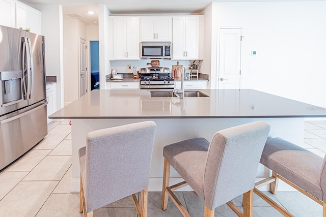 kitchen featuring appliances with stainless steel finishes, a sink, white cabinets, a breakfast bar, and recessed lighting
