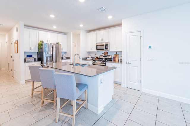 kitchen featuring appliances with stainless steel finishes, a breakfast bar area, a sink, a center island with sink, and recessed lighting