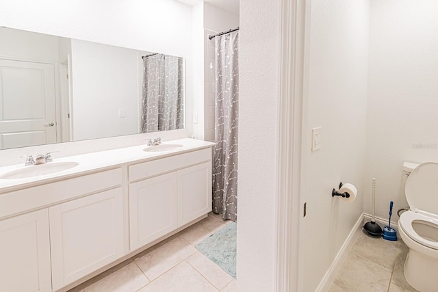 full bathroom featuring toilet, tile patterned floors, double vanity, and baseboards