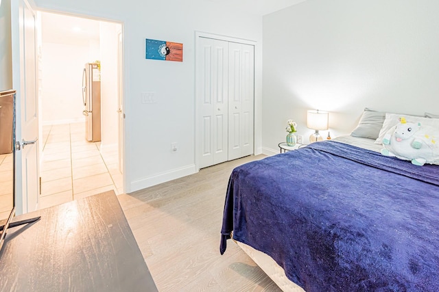 bedroom featuring freestanding refrigerator, baseboards, and a closet