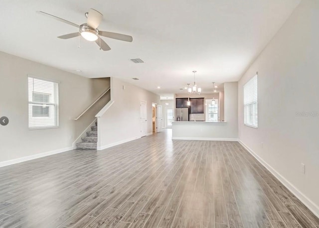 11807 Charades St, Orlando, FL 32832 - unfurnished living room with wood finished floors, stairway, a chandelier, and healthy amount of natural light